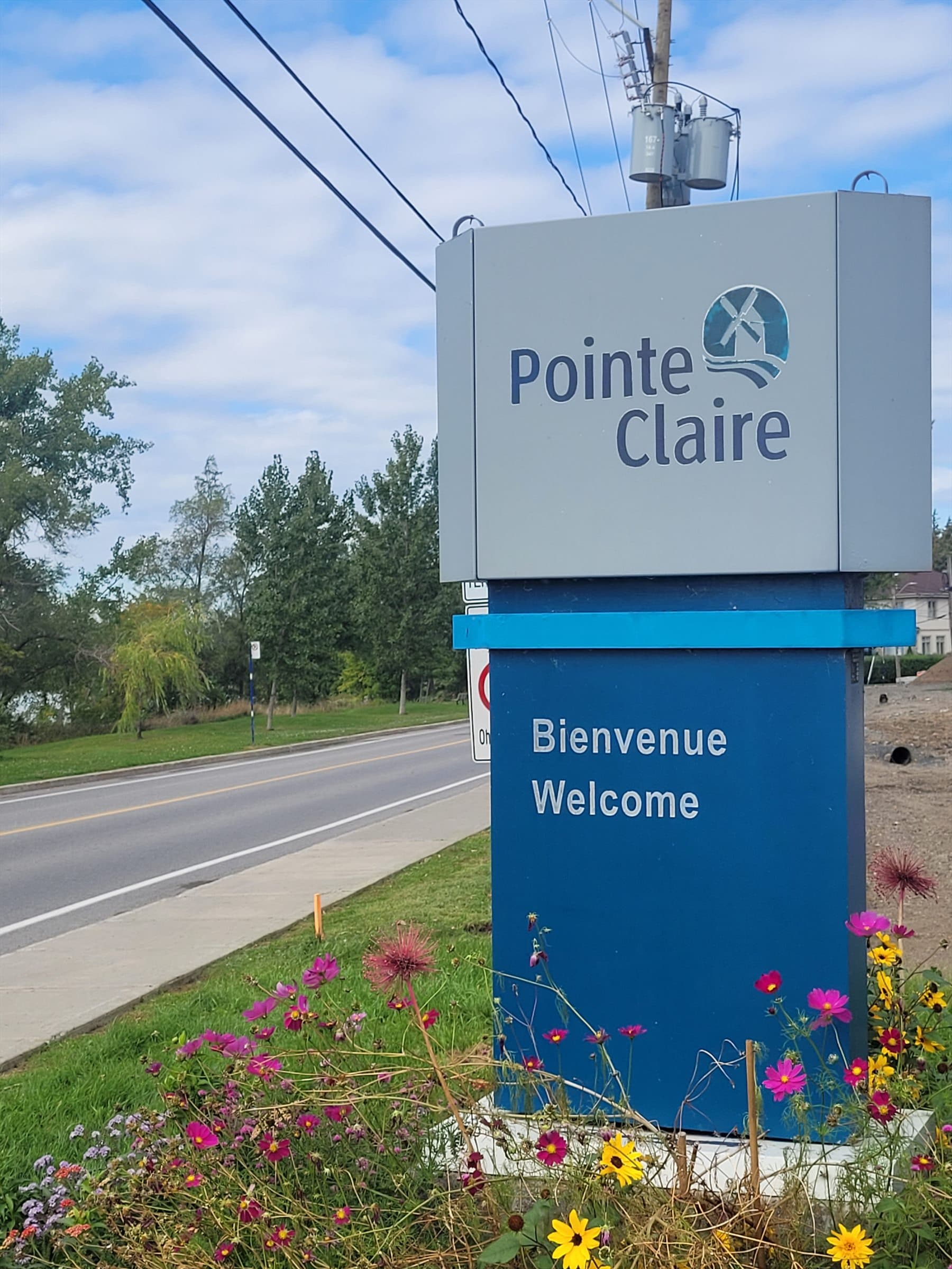 Pointe-Claire welcome sign beside a residential street and flower bed